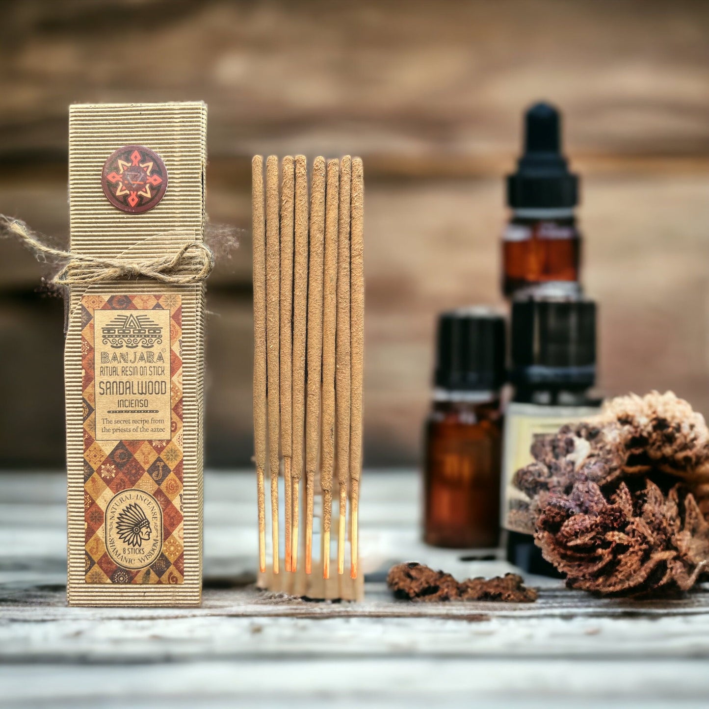 Incense sticks with packaging, essential oil bottles, and dried plants on a wooden surface.
