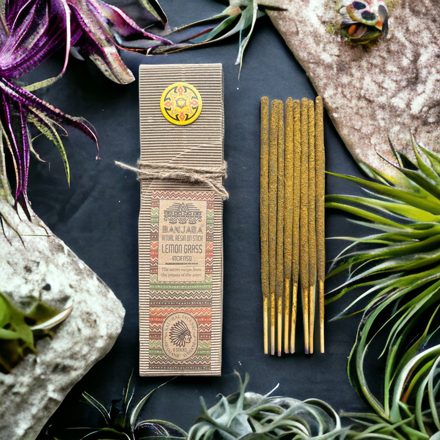 Incense sticks with packaging on a dark surface surrounded by plants