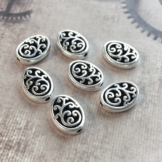 Silver beads with intricate patterns on a textured surface