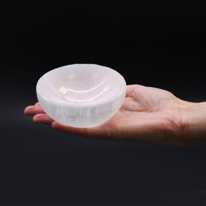 Hand holding a translucent crystal bowl against a black background