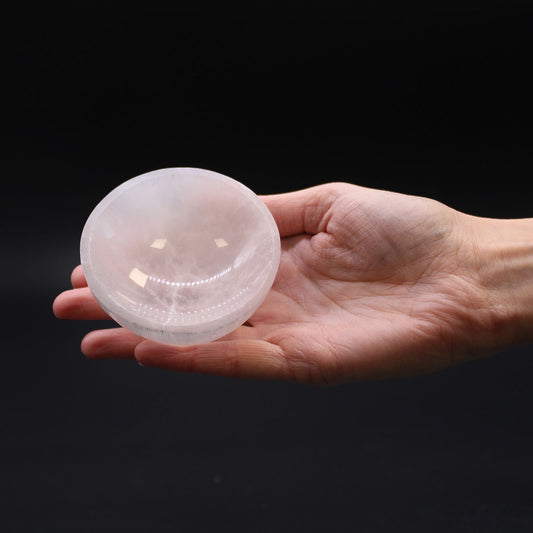 Hand holding a clear crystal ball against a black background