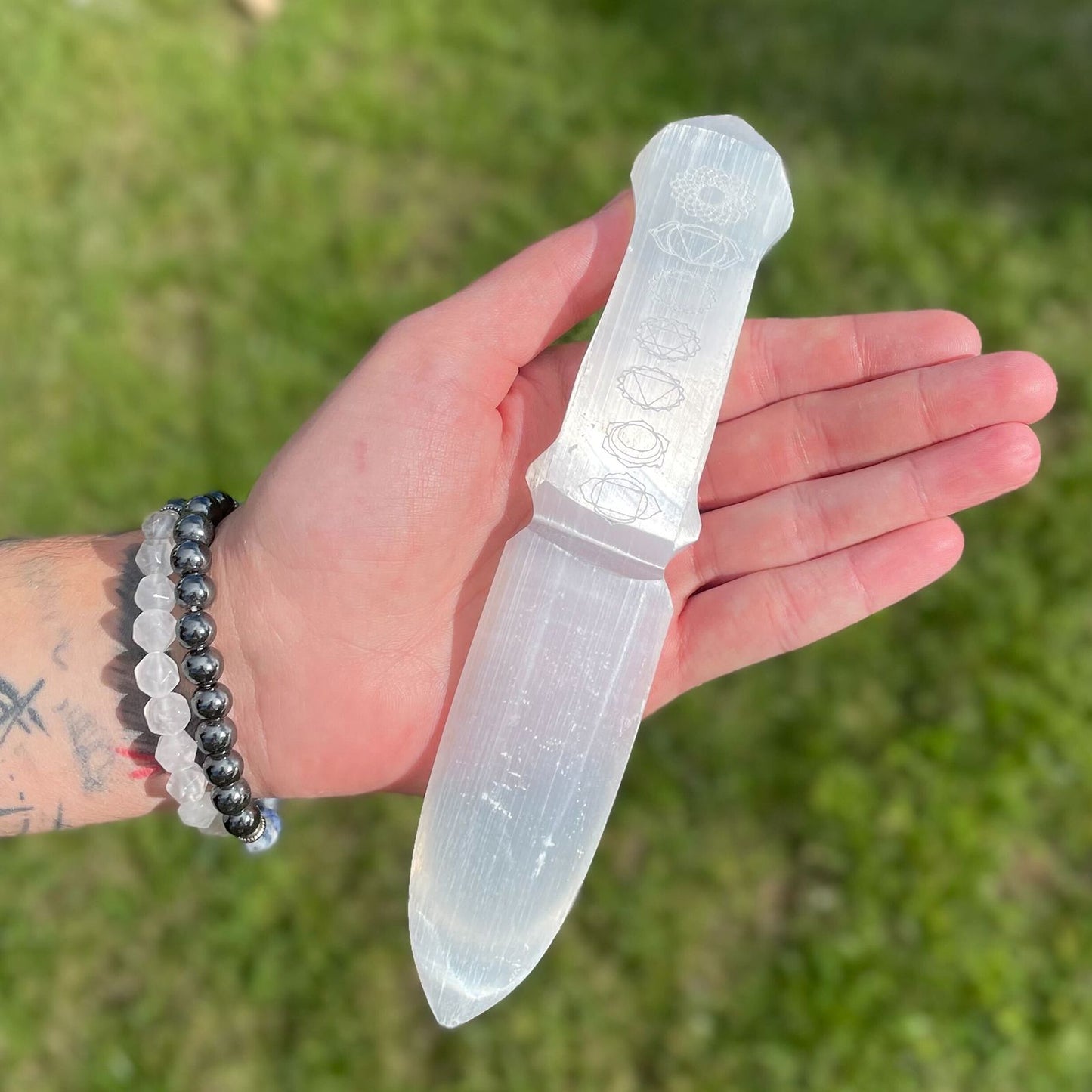 Clear crystal knife held in a hand with a blurred green background